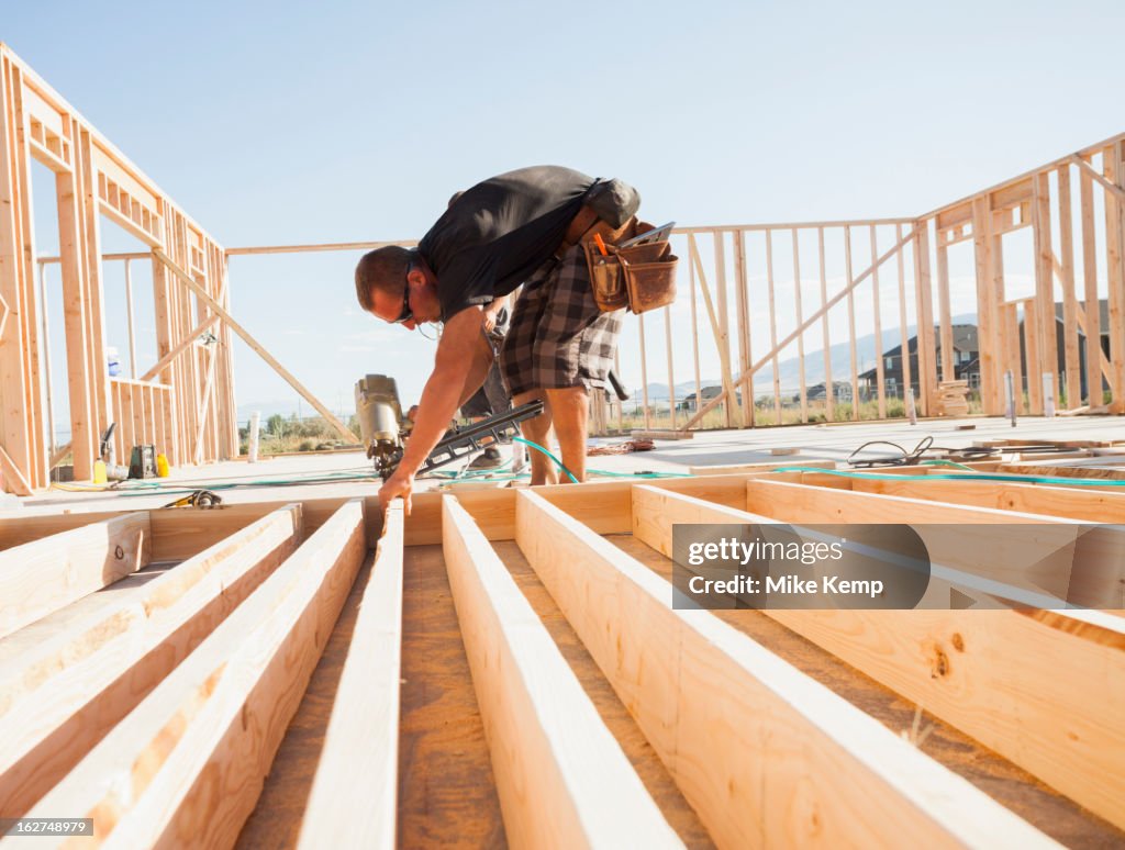 Caucasian man using nail gun on frame