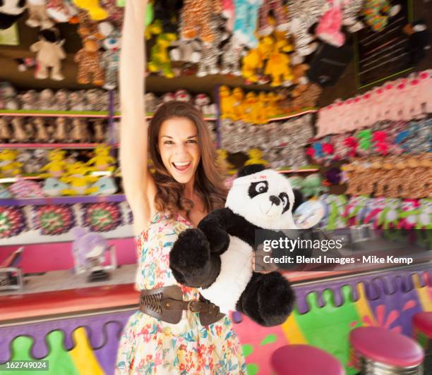 caucasian woman holding stuffed animal at carnival - animal win stock-fotos und bilder