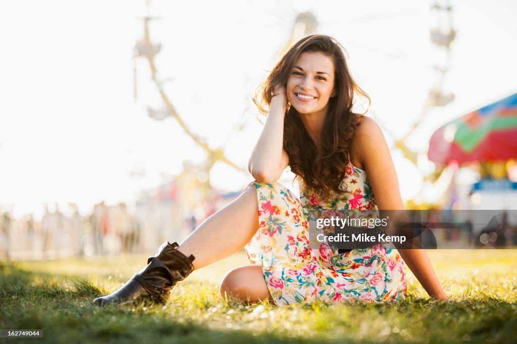 Caucasian woman sitting in grass at carnival