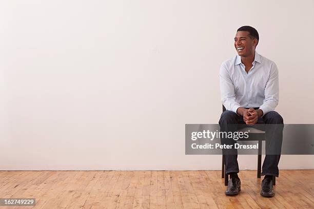 black man sitting in chair - man chair stockfoto's en -beelden