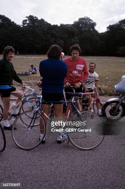 The Bike. France- août 1974- le cyclisme: cycliste en tenue, tenant leur vélo, à l'arrêt sur une route, aux abords d'un parc.