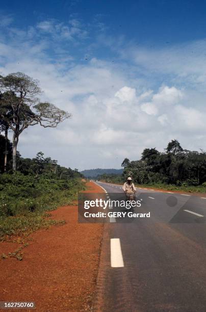 The French Guiana. En Guyane française, en février 1975, une personne roulant en mobylette sur une route de campagne.