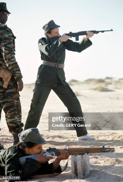 Mariem Daddah Practicing Rifle Shooting. En Mauritanie, en novembre 1977, debout aux côtés d'un militaire, Mariem DADDAH en uniforme, alias...