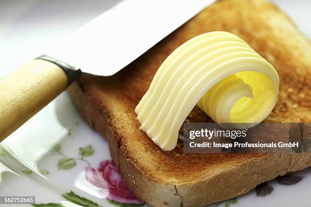 slice of toast with curl of butter - butter curl stock pictures, royalty-free photos & images