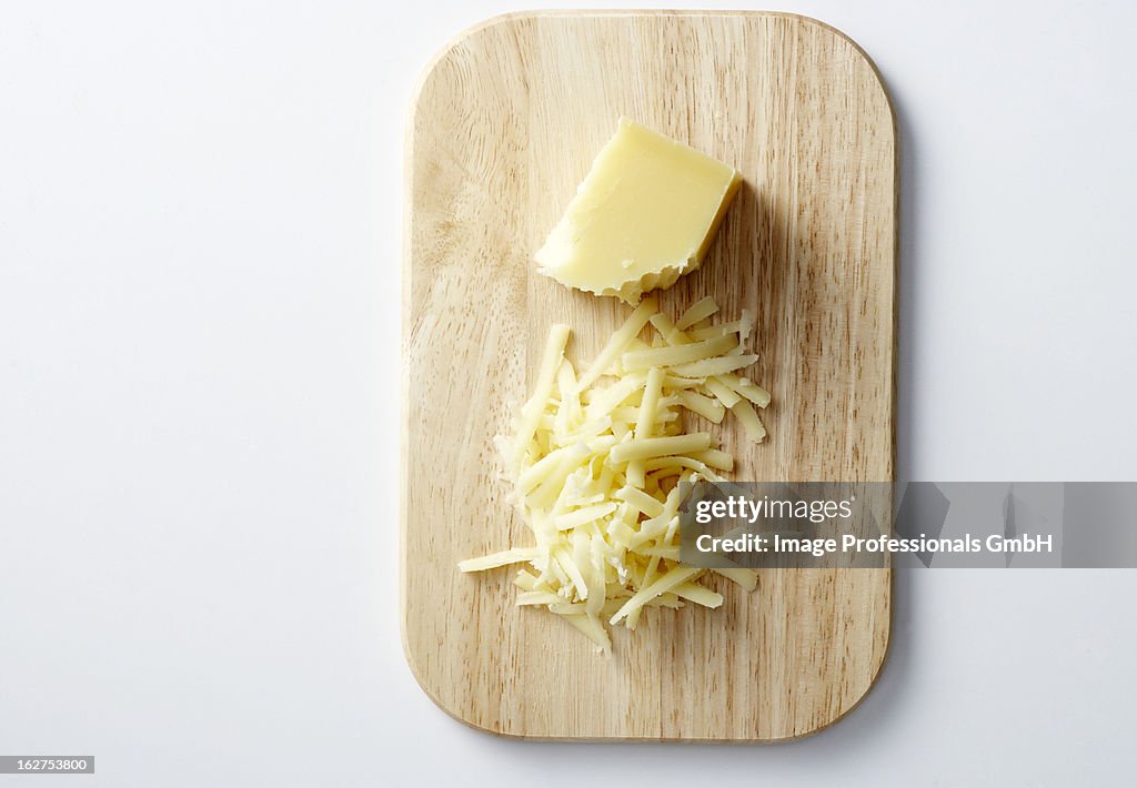 Gruyere, partially grated, on chopping board, overhead view