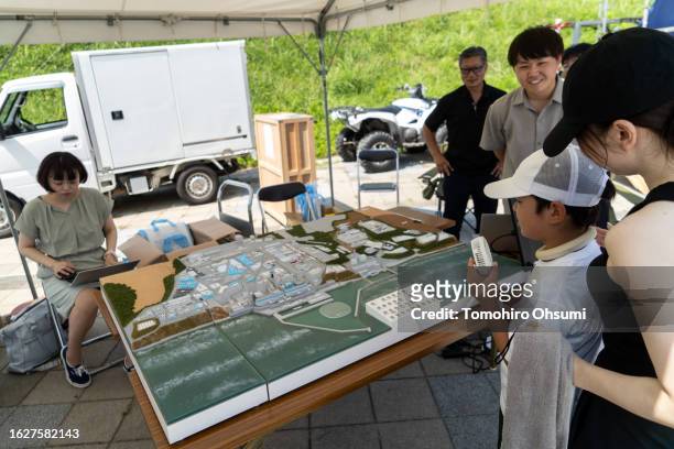 Boy and his mother look at a model of the Fukushima Daiichi Nuclear Power Station in the government booth during the Iwasawa Surfing Games at Iwasawa...