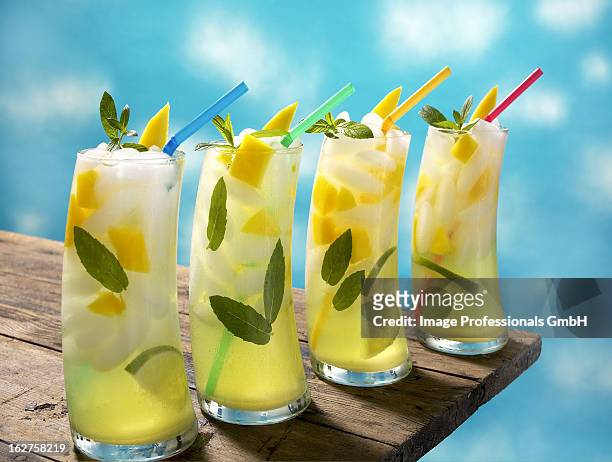 four mango lime mojitos with straws on table - 4 cocktails stockfoto's en -beelden