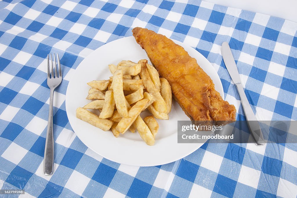 Close-up of fries and meat with fork and table knife on table