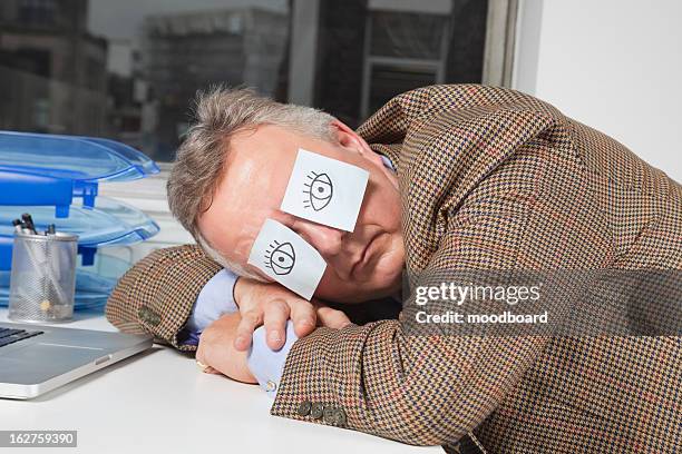 businessman sleeping with sticky notes on eyes at desk in office - napping stock pictures, royalty-free photos & images