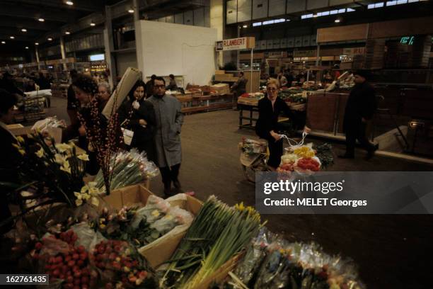 The Halls Of Rungis. En France, à Rungis, en janvier 1970, dans les halles du marché, une femme portant des lunettes, sur son vélo, transportant des...