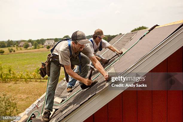 workman install roof on rural building - waterproof photos et images de collection