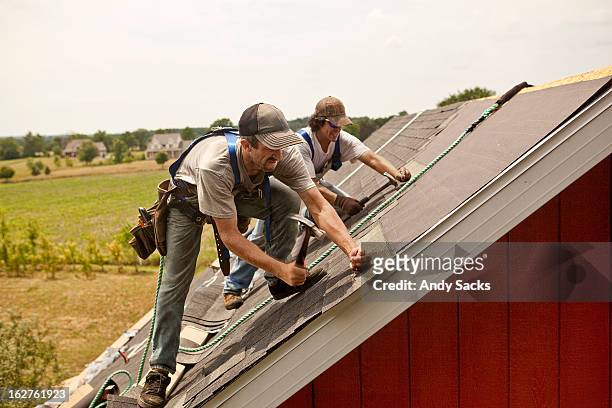 workman install roof on rural building - muster stock pictures, royalty-free photos & images