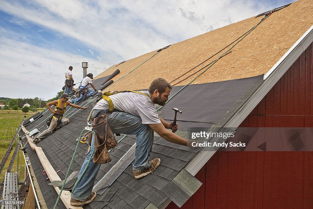 Workman install roof on rural building