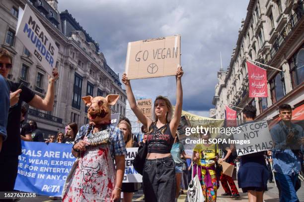 Protester holds a 'Go vegan' placard and another protester wears a pig mask during the demonstration in Regent Street. Crowds marched through central...