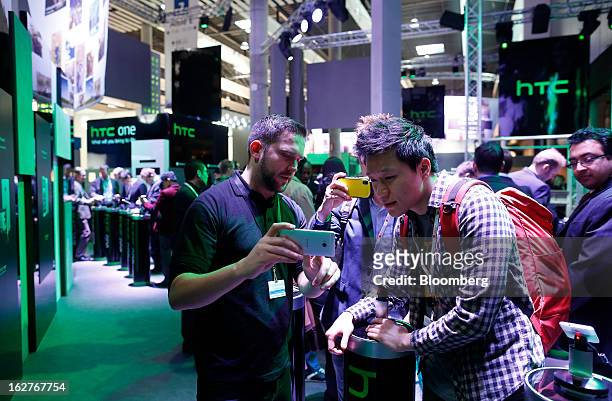 An employee demonstrates HTC Corp. One Touch smartphones to visitors at the Mobile World Congress in Barcelona, Spain, on Tuesday, Feb. 26, 2013. The...