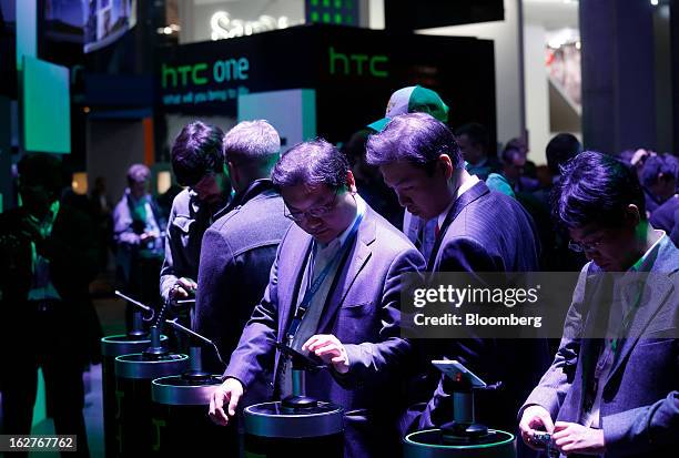 Visitors inspect HTC Corp. One smartphones on display at the Mobile World Congress in Barcelona, Spain, on Tuesday, Feb. 26, 2013. The Mobile World...