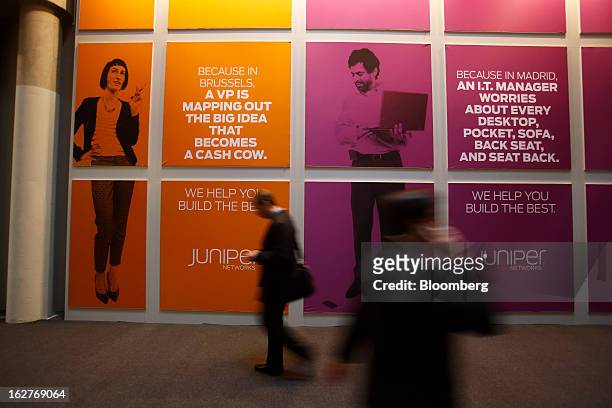 Visitors pass advertising banners outside the Juniper Networks Inc. Pavilion at the Mobile World Congress in Barcelona, Spain, on Tuesday, Feb. 26,...