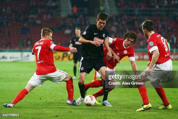 Johannes Flum of Freiburg is challenged by Niki Zimling, Julian Baumgartlinger and Radoslav Zabavnik of Mainz during the DFB Cup Quarter Final match...