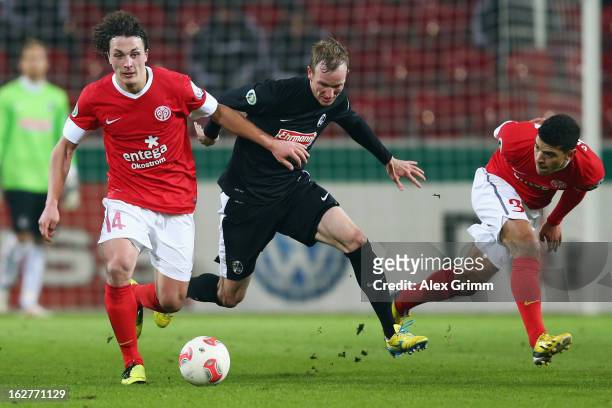 Jan Rosenthal of Freiburg is challenged by Julian Baumgartlinger and Shawn Parker of Mainz during the DFB Cup Quarter Final match between FSV Mainz...