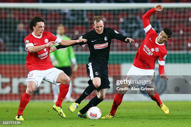 Jan Rosenthal of Freiburg is challenged by Julian Baumgartlinger and Shawn Parker of Mainz during the DFB Cup Quarter Final match between FSV Mainz...