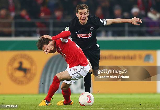 Nicolai Mueller of Mainz is challenged by Julian Schuster of Freiburg during the DFB Cup Quarter Final match between FSV Mainz 05 and SC Freiburg at...