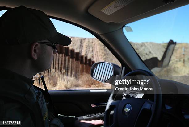 Border Patrol agent looks along a section of the recently-constructed fence at the U.S.-Mexico border on February 26, 2013 in Nogales, Arizona. The...