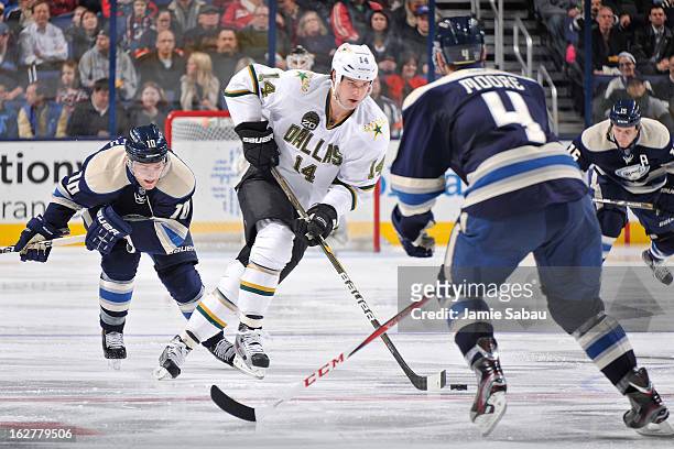 Jamie Benn of the Dallas Stars carries the puck up ice as Mark Letestu of the Columbus Blue Jackets and John Moore of the Columbus Blue Jackets...