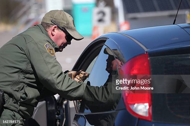 Border Patrol agent prepares to search a car entering the United States from Mexico on February 26, 2013 in Nogales, Arizona. Some 15,000 people...