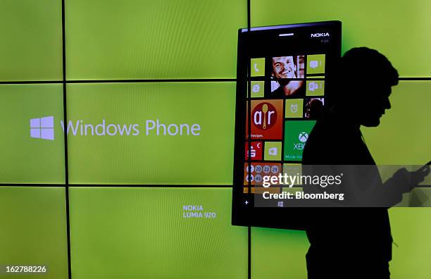 Visitor checks his mobile device in front of a video advertisement for a Nokia Lumia 920 Windows Phone at a media event at the Hotel Rey San Carlos...