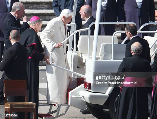 Pope Benedict XVI is helped onto the Pope Mobile by his personal secretary Bishop Georg Gaenswein in St Peter's Square on February 27, 2013 in...