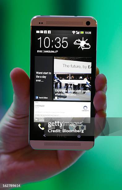An employee holds an HTC Corp. One Touch smartphone for a photograph at the Mobile World Congress in Barcelona, Spain, on Wednesday, Feb. 27, 2013....