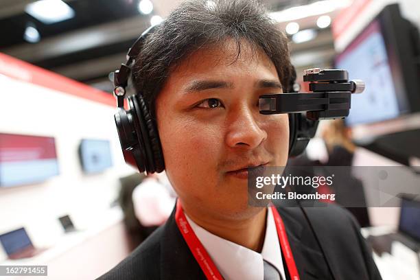 An employee uses a Laser Head Set to test an audio-visual headphone system in the Fujitsu Ltd. Pavilion at the Mobile World Congress in Barcelona,...