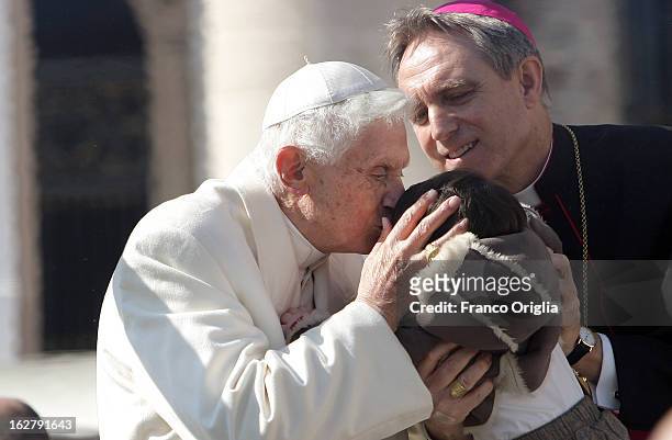 Pope Benedict XVI kisses a child lifted up by the Pontiff's personal secretary Georg Ganswein, as he leaves St. Peter's Square at the end of his...