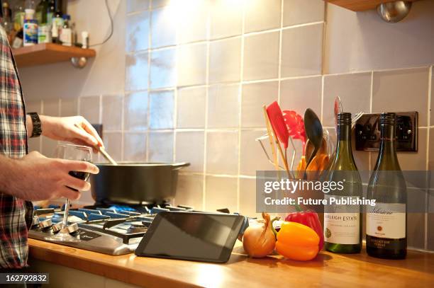 Man using an Apple iPad Mini tablet computer in a kitchen setting, January 17, 2013.