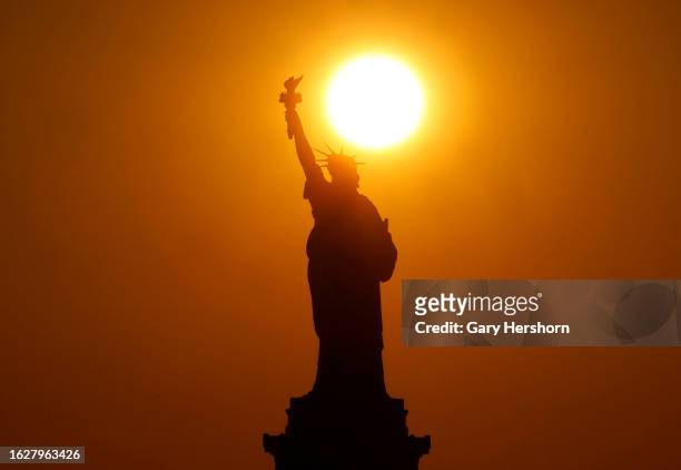 The sun sets behind the Statue of Liberty on August 19 in New York City.