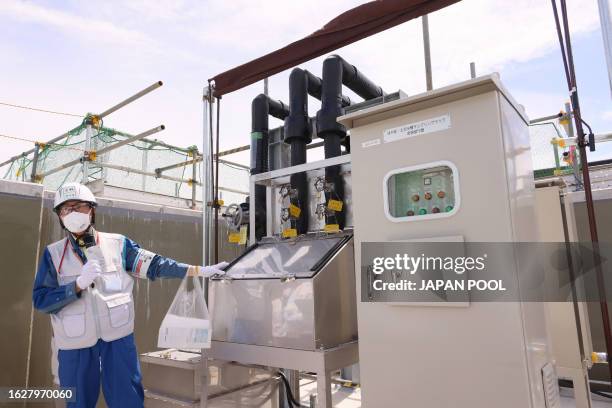 An official demonstrates an equipment for sampling water to analyze the concentration of radioactive tritium before discharging diluted treated...