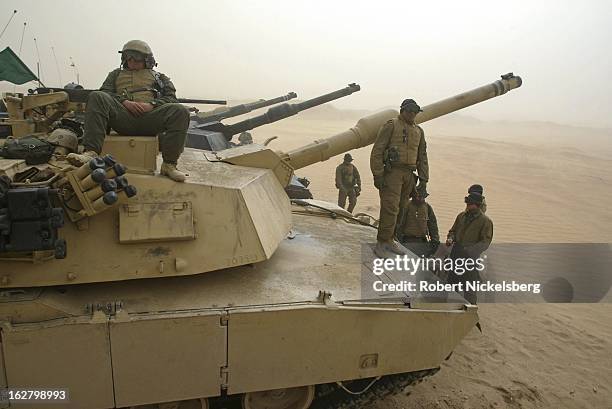 Marines from the 1st Marine Division rest on top of their M1A1 Abrams tanks February 3, 2003 during a sandstorm waiting for sighting in exercises to...