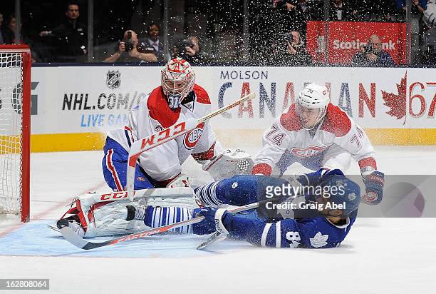 Carey Price and Alexei Emelin of the Montreal Canadiens defend as Mikhail Grabovski of the Toronto Maple Leafs crashes the goal during NHL game...