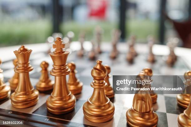 golden pieces stand and set with another pieces on chess board - chessmen stock pictures, royalty-free photos & images