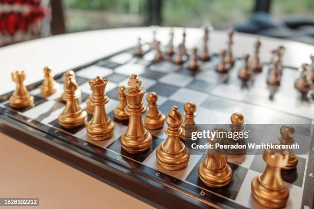 golden pieces stand and set with another pieces on chess board - chessmen stock pictures, royalty-free photos & images