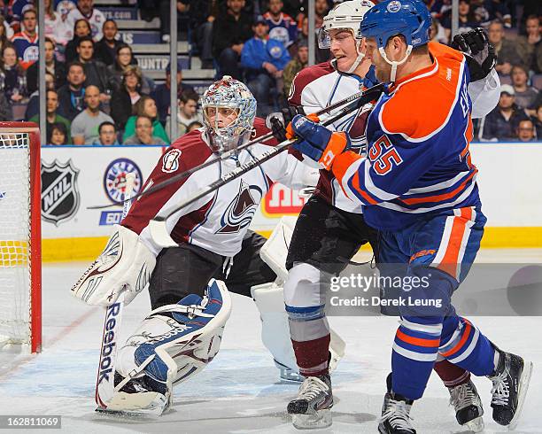 Ben Eager of the Edmonton Oilers battles for position against Tyson Barrie of the Colorado Avalanche while in front of the net of Avalanche goalie...