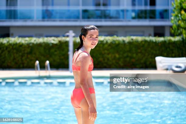 a girl stands outside the pool looking sideways at the camera - girls flashing camera stock-fotos und bilder