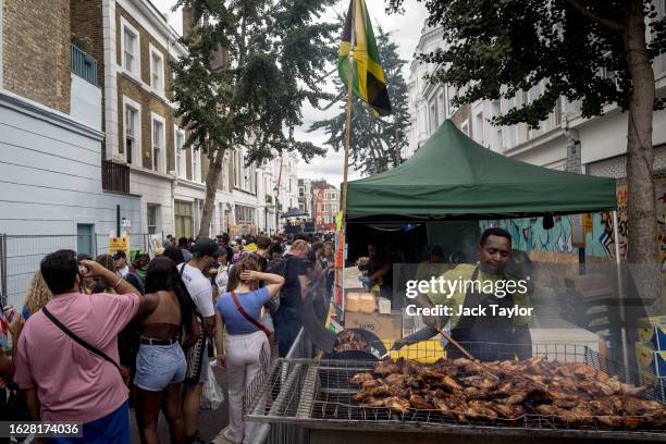 Man cooks jerk chicken on a barbecue on families and children's day at Notting Hill Carnival on August 27, 2023 in London, England. The annual...