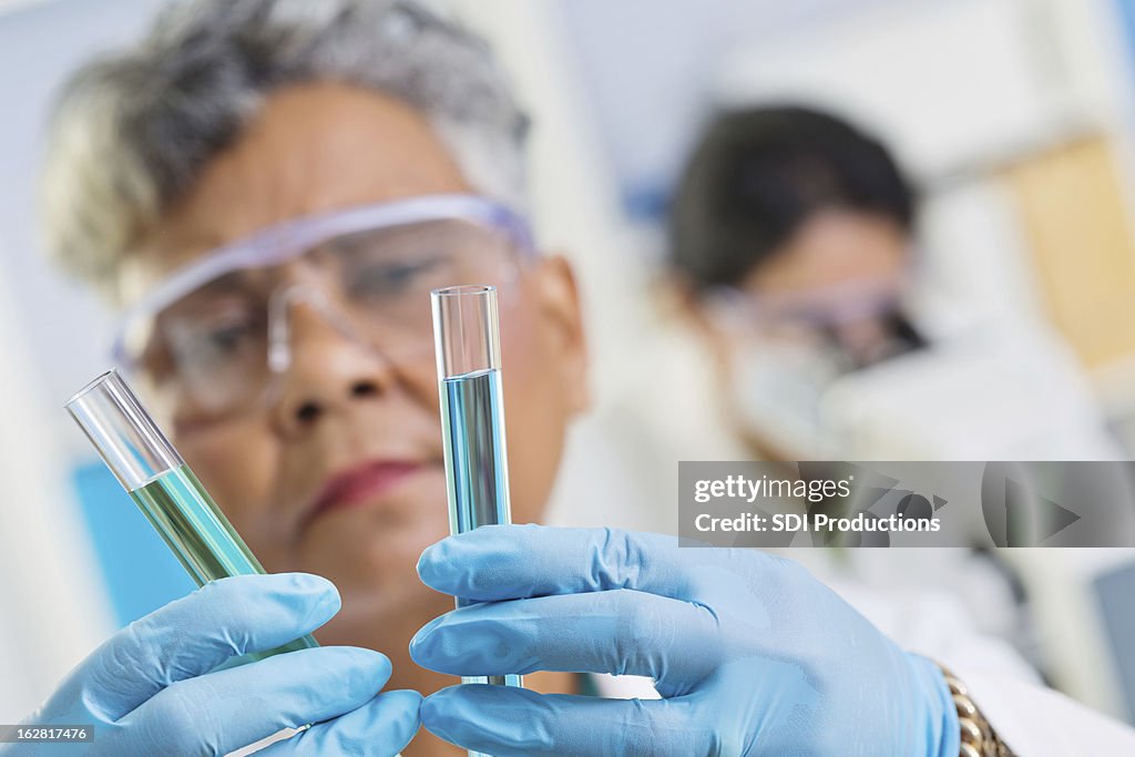 Chemist combining chemicals in test tubes at science lab
