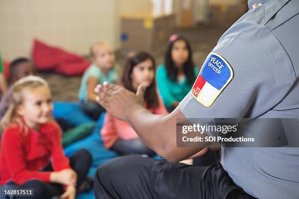 closeup of police officer talking to young class on campus - friendly police stock pictures, royalty-free photos & images