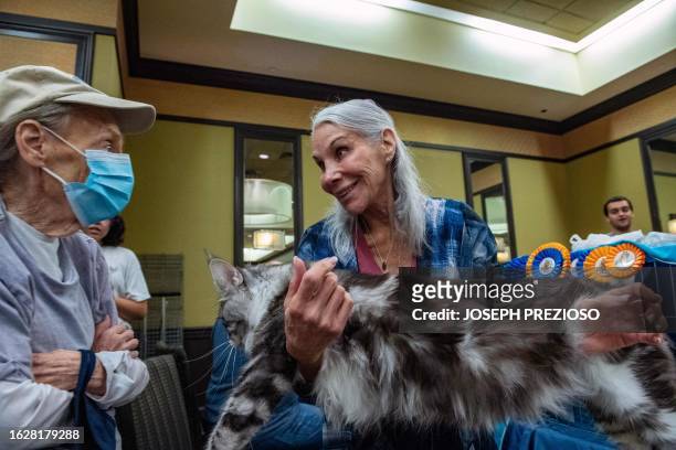 Bonnie Pilar shows her Maine Coon cat to an attendee during the New England Meow Outfit's 10th Annual Allbreed and Household Pet Cat Show in Natick,...
