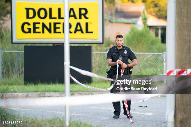 Police officer adjusts crime scene tape outside the Dollar General store where three people were shot and killed the day before on August 27, 2023 in...