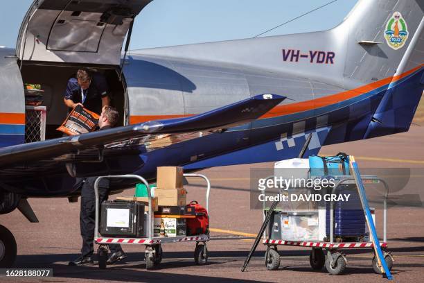 Police personnel load equipments onto a Northern Territory Police plane on the tarmac of the Darwin International Airport in Darwin on August 28 as...