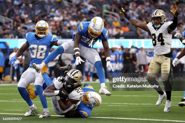 Kendre Miller of the New Orleans Saints runs for a touchdown against a jumping Ja'Sir Taylor, Cam Brown and Daiyan Henley of the Los Angeles Chargers...