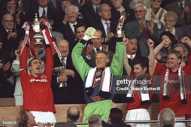 Eric Cantona of Manchester United holds aloft the trophy and Peter Schmeical Denis Irwin and David May all of Manchester United celebrate after...